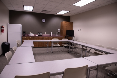 Lobby meeting room with kitchenette along back wall and table and chairs in main area
